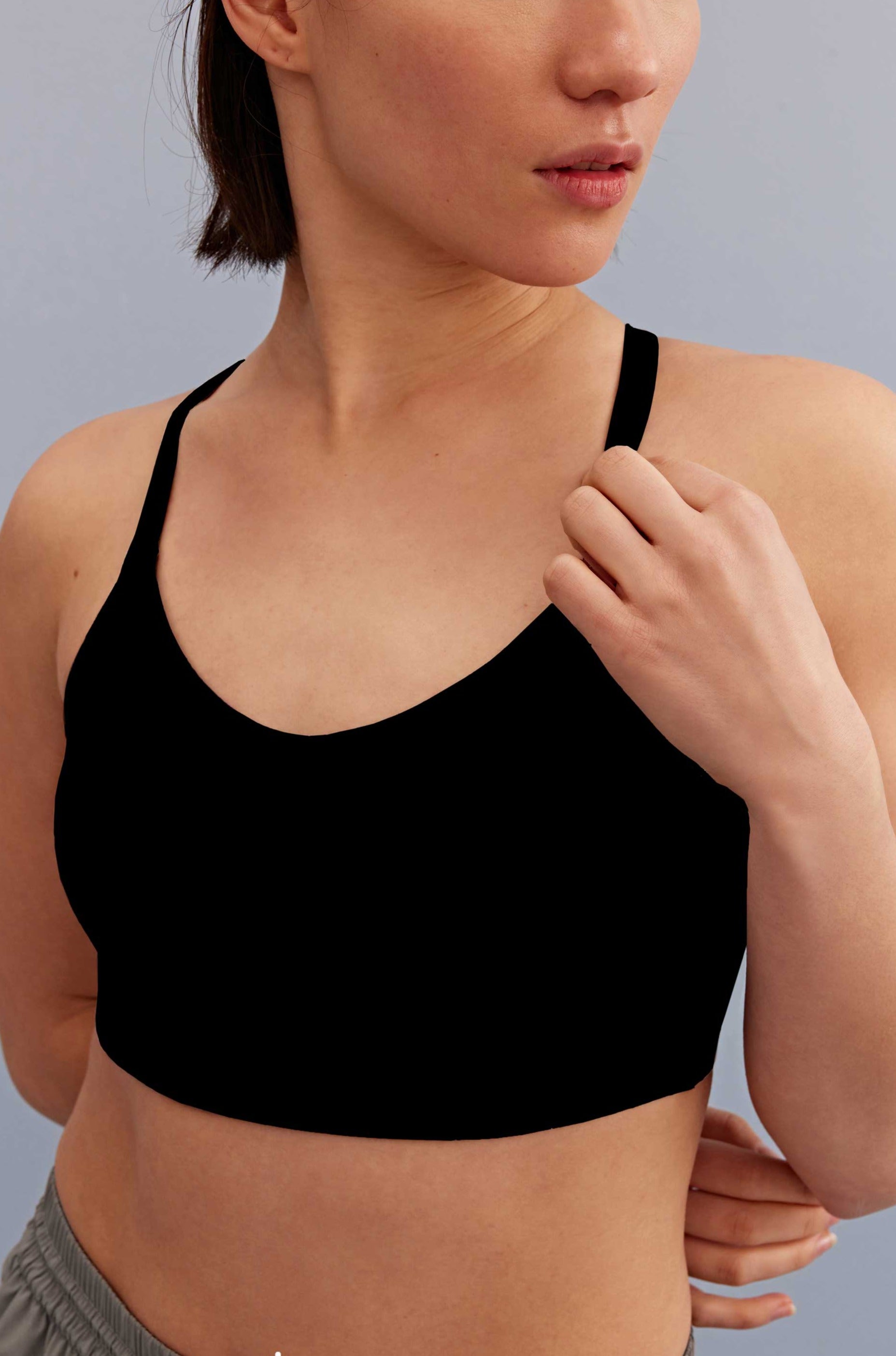 a woman holding the strap of the black sports bra