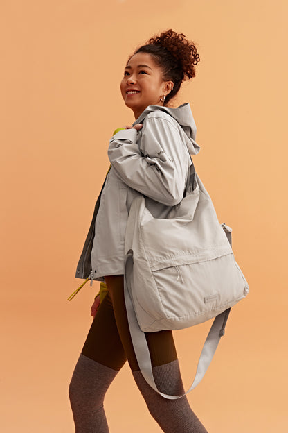 a woman wearing a grey jacket and grey bag