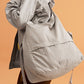 a woman wearing a grey jacket and grey bag