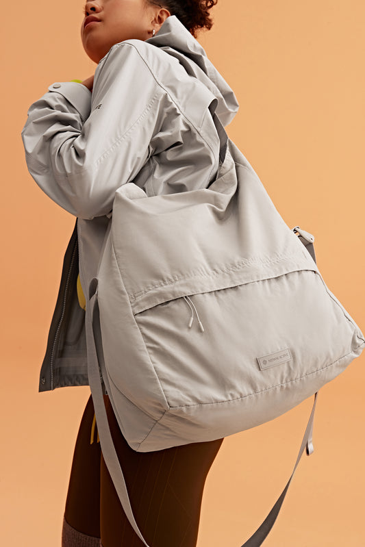 a woman wearing a grey jacket and grey bag