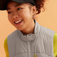 a woman wearing black visor and grey vest with green sweatshirt under