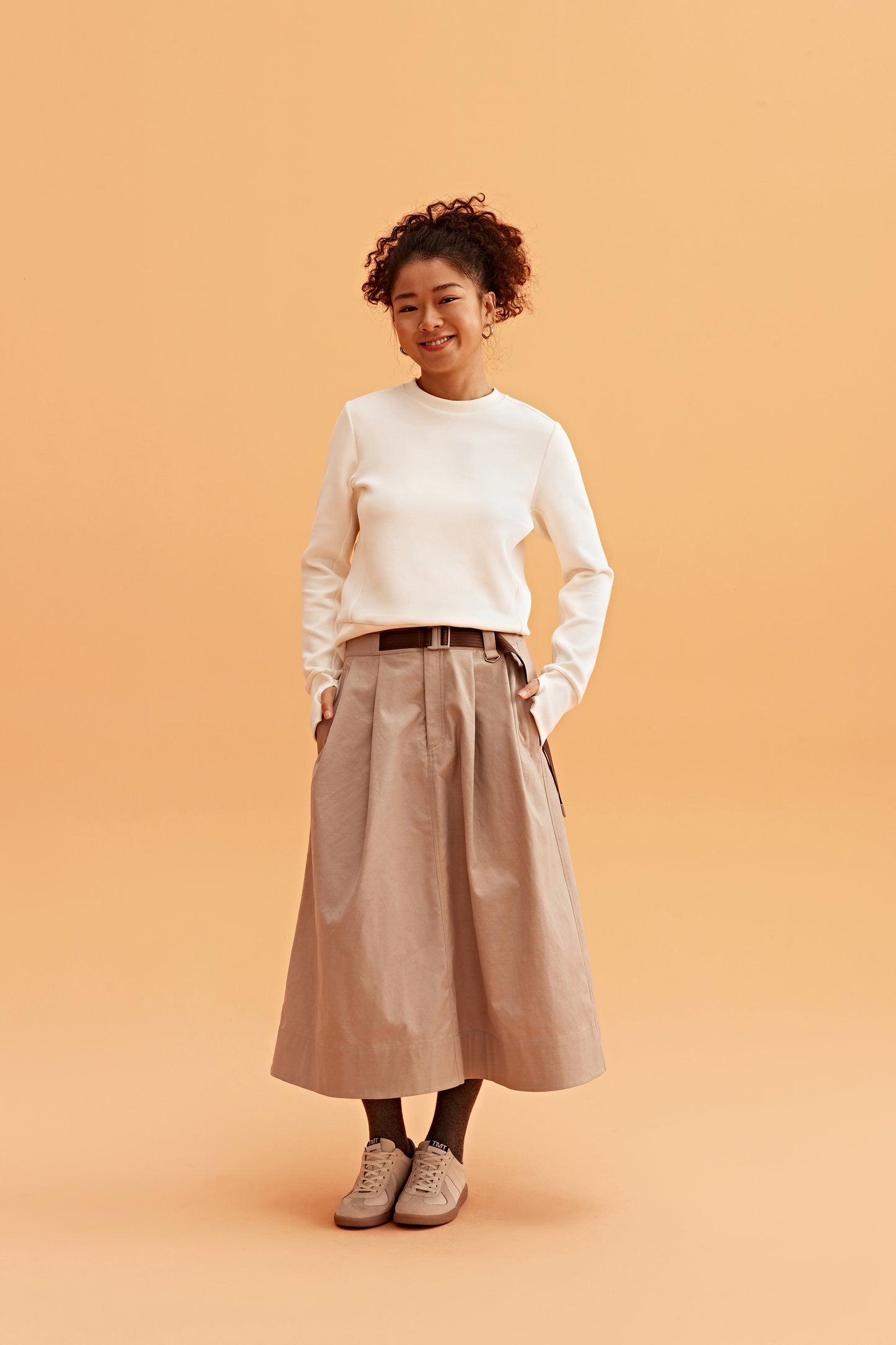 woman wearing a white sweatshirt and brown skirts.