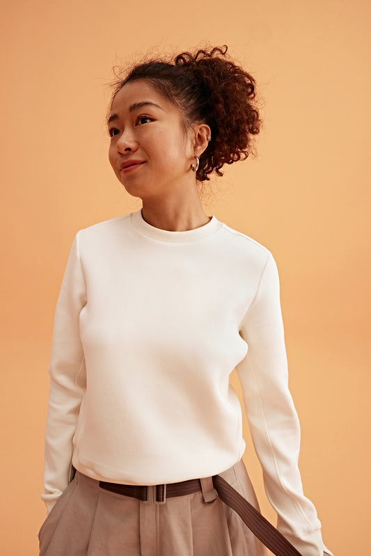woman wearing a white sweatshirt and brown skirts.