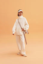woman wearing a white visor and white half zip sweatshirt and white pants. pair with a white sneakers