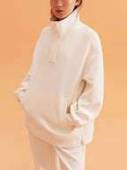 woman wearing a white visor and white half zip sweatshirt and white pants.