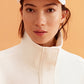 closeup shot of woman wearing a white visor and white sweatshirt 