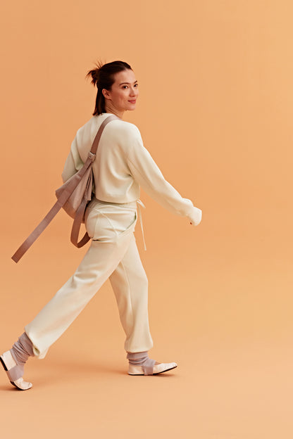 woman wearing a white visor and white half zip sweatshirt and white pants. 