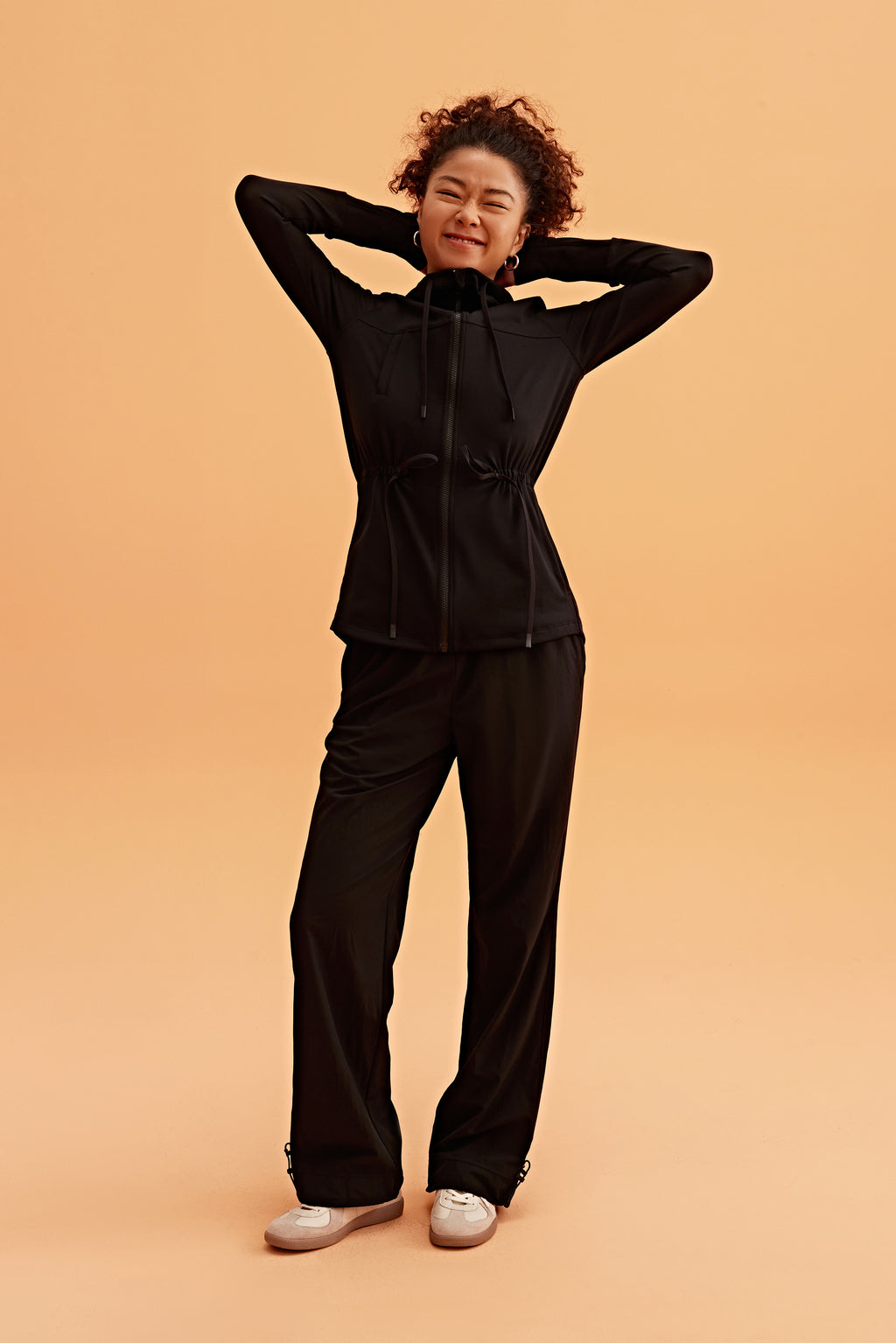 a woman wearing a light black hooded jacket and black pants