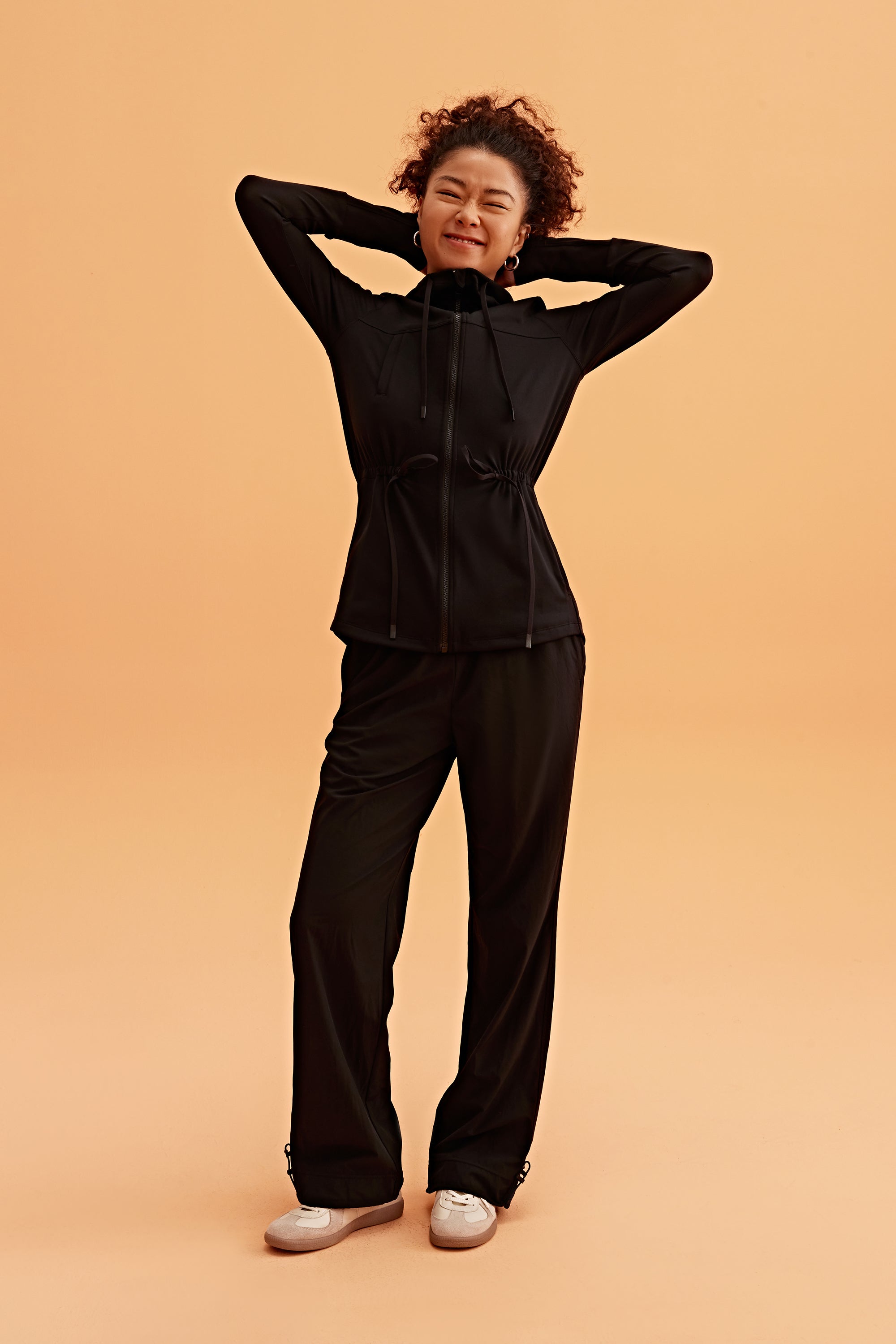 a woman wearing a light black hooded jacket and black pants