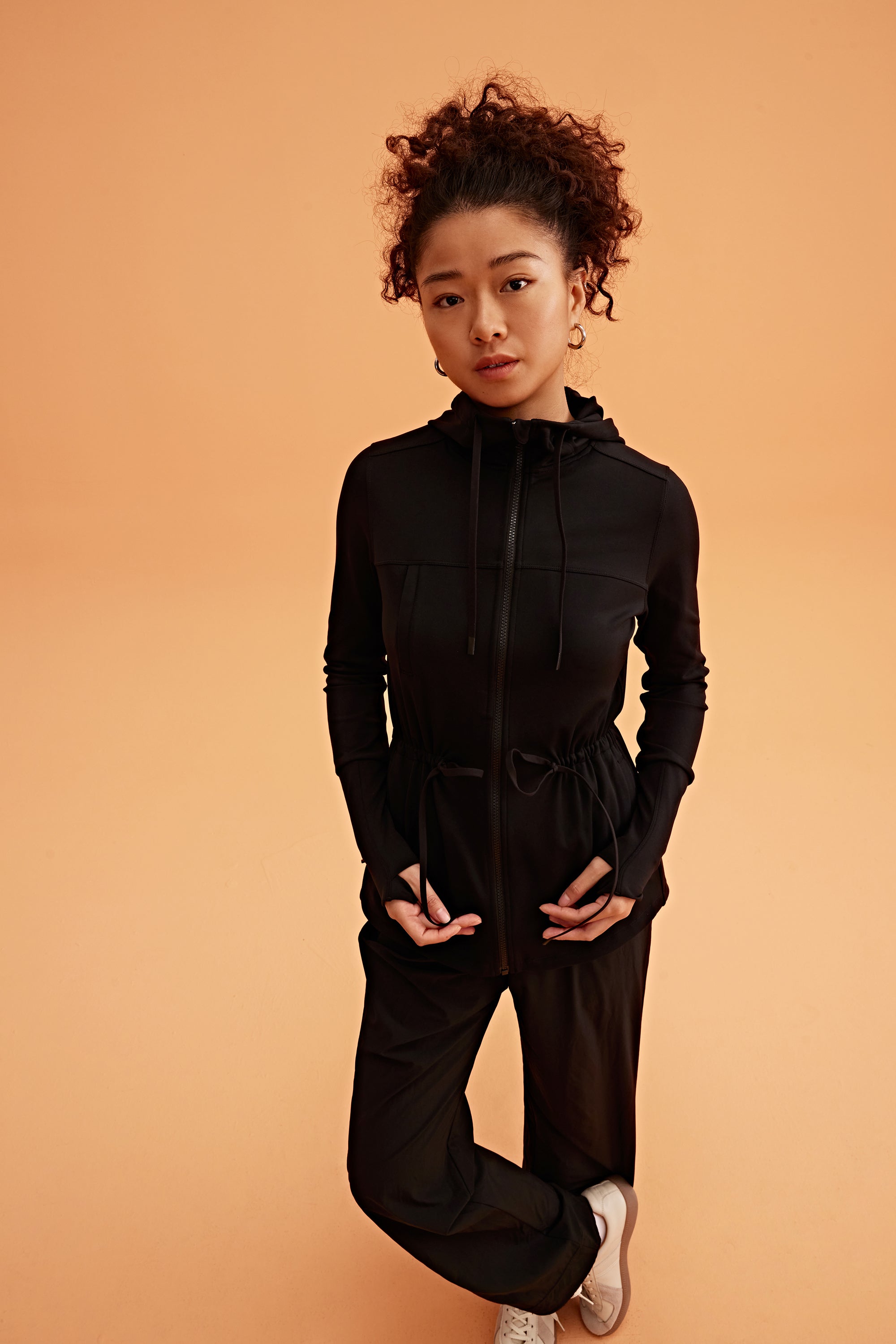 a woman wearing a light black hooded jacket and black pants