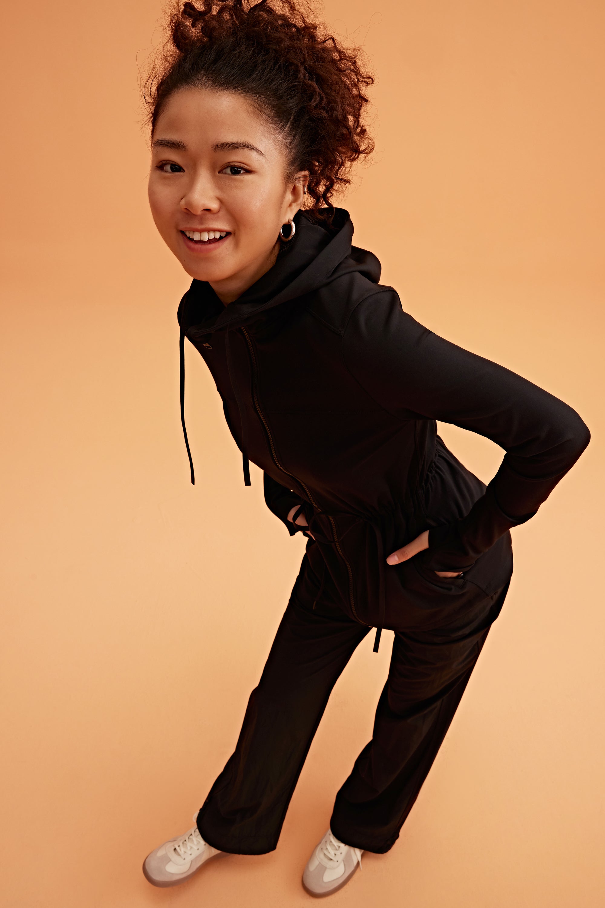 a woman wearing a light black hooded jacket and black pants