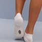 a person wearing white socks, lifting left foot to show the neiwai active logo