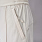 A close-up view of off-white pants, highlighting the elastic waistband and side pocket with drawstring detail. The fabric and stitching details are clearly visible, showcasing the design