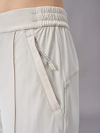 A close-up view of off-white pants, highlighting the elastic waistband and side pocket with drawstring detail. The fabric and stitching details are clearly visible, showcasing the design