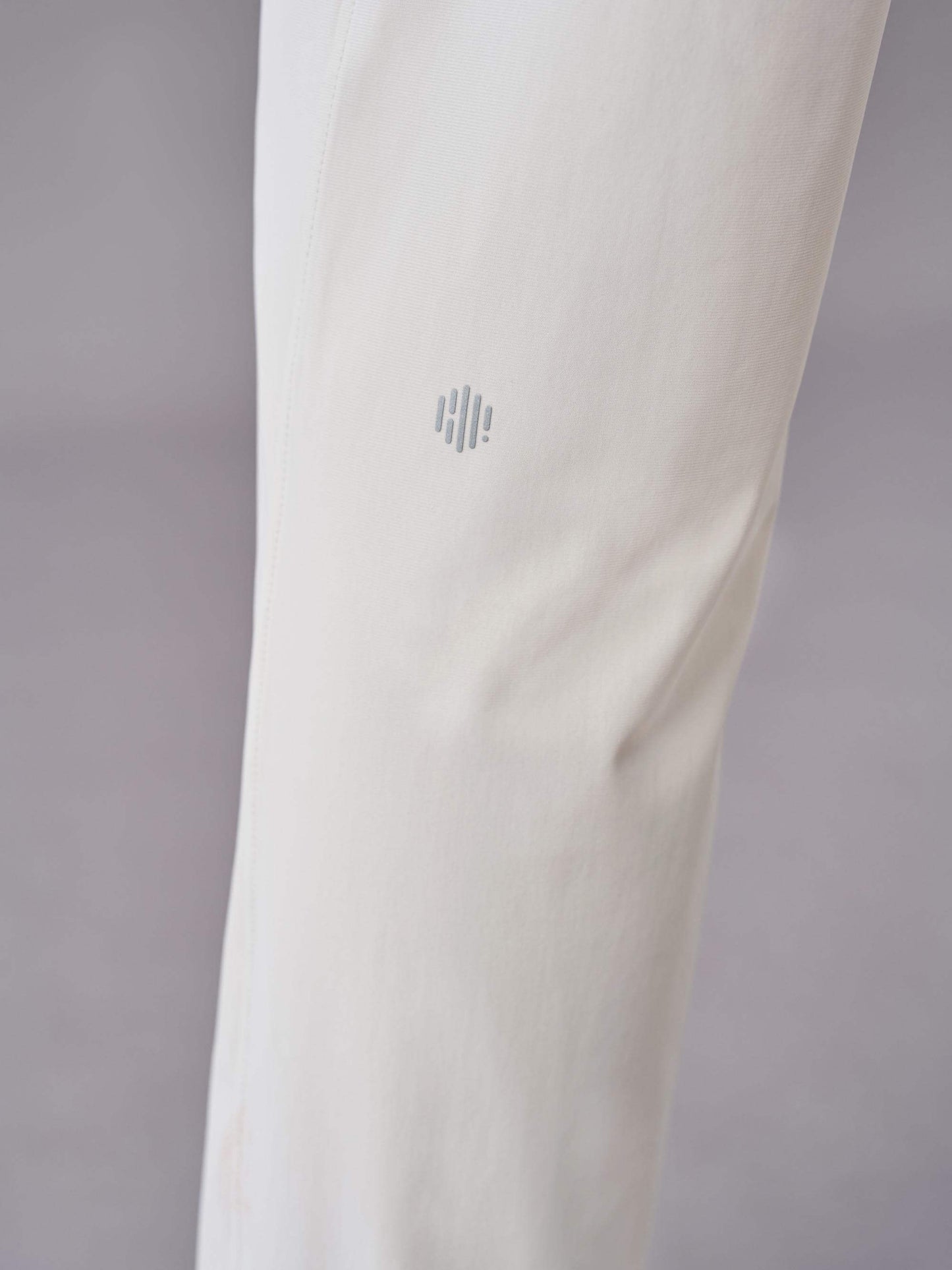 Close-up of off-white pants showcasing the subtle logo detail near the knee area.