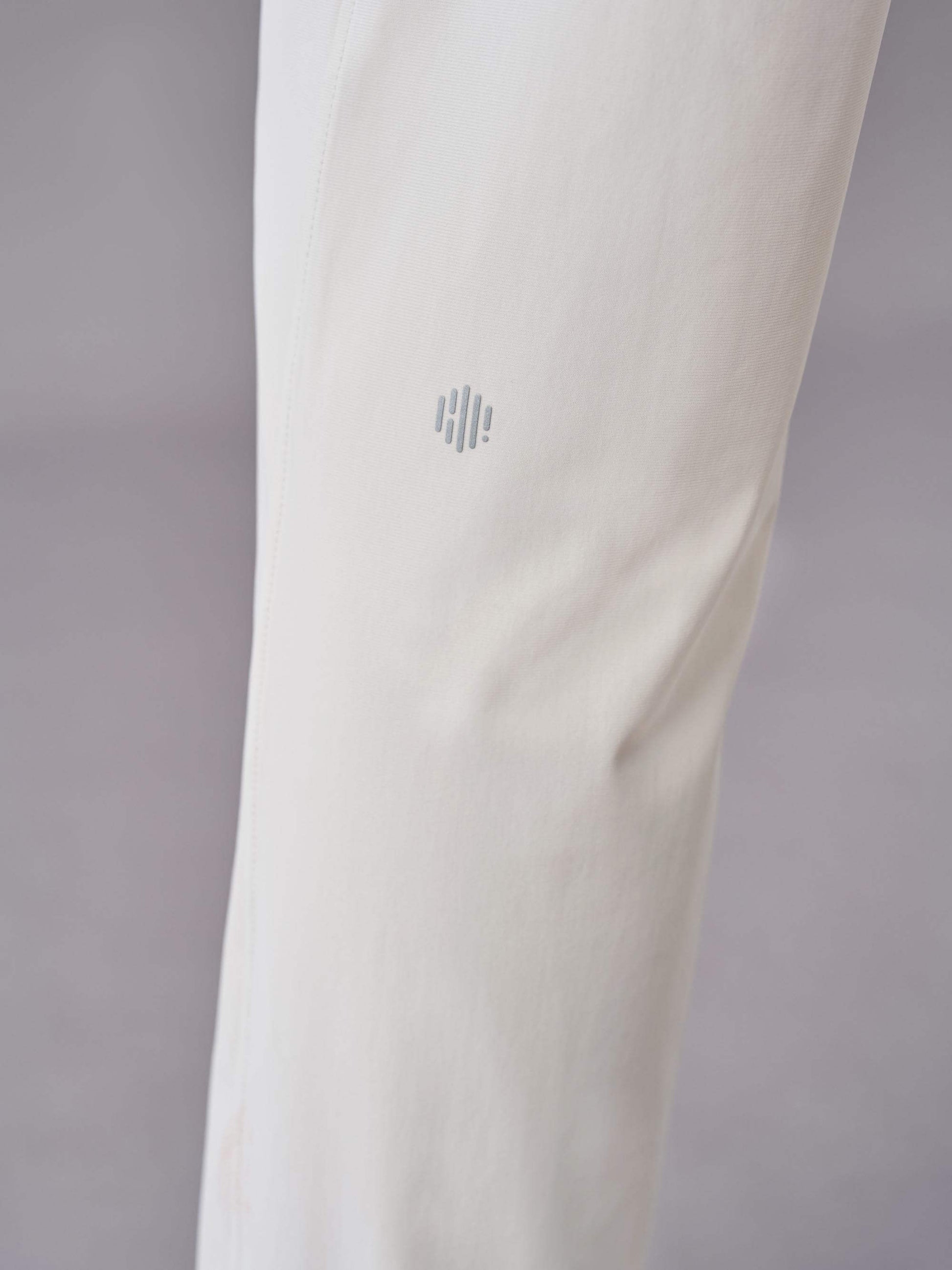 Close-up of off-white pants showcasing the subtle logo detail near the knee area.