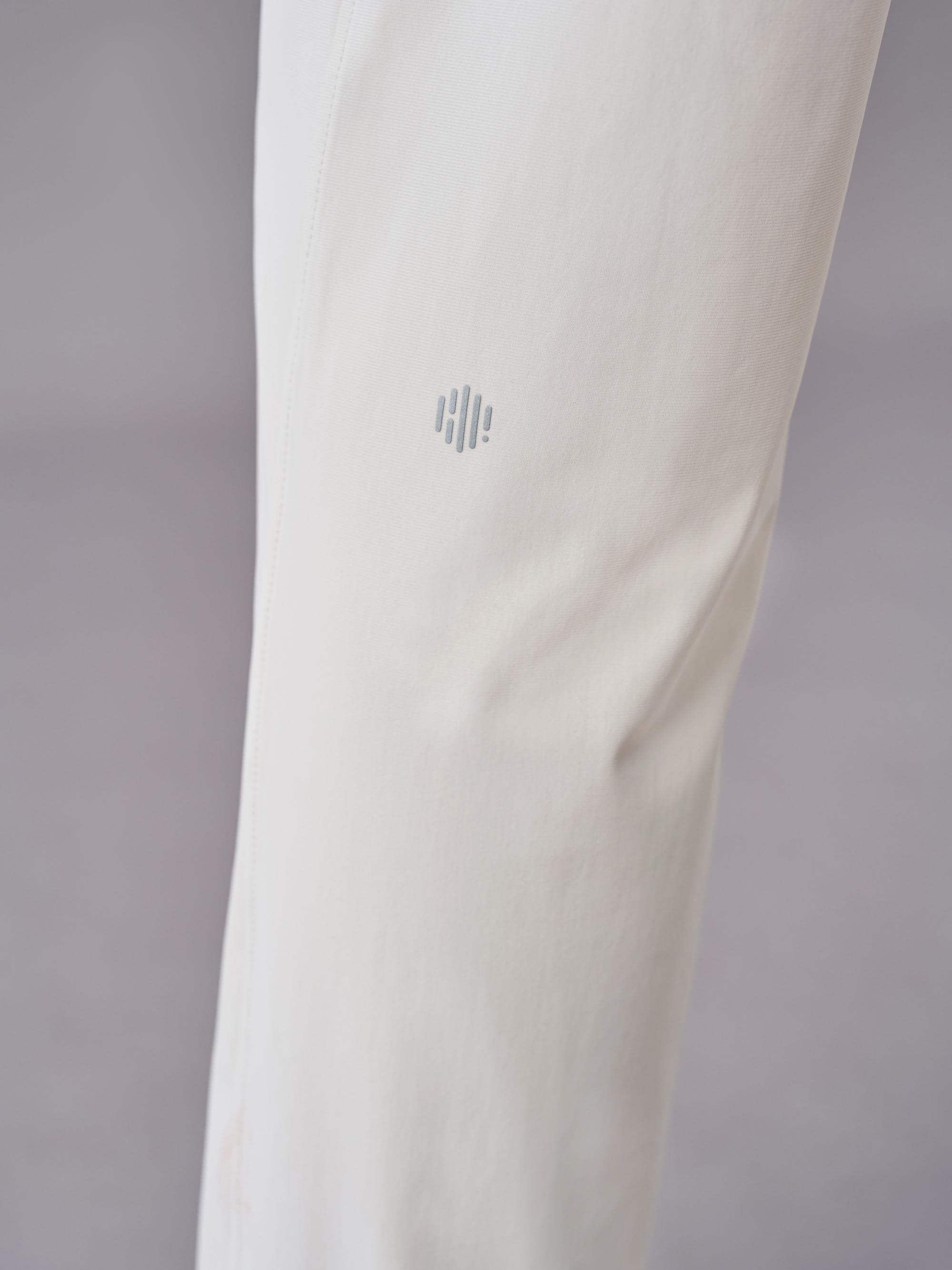 Close-up of off-white pants showcasing the subtle logo detail near the knee area.