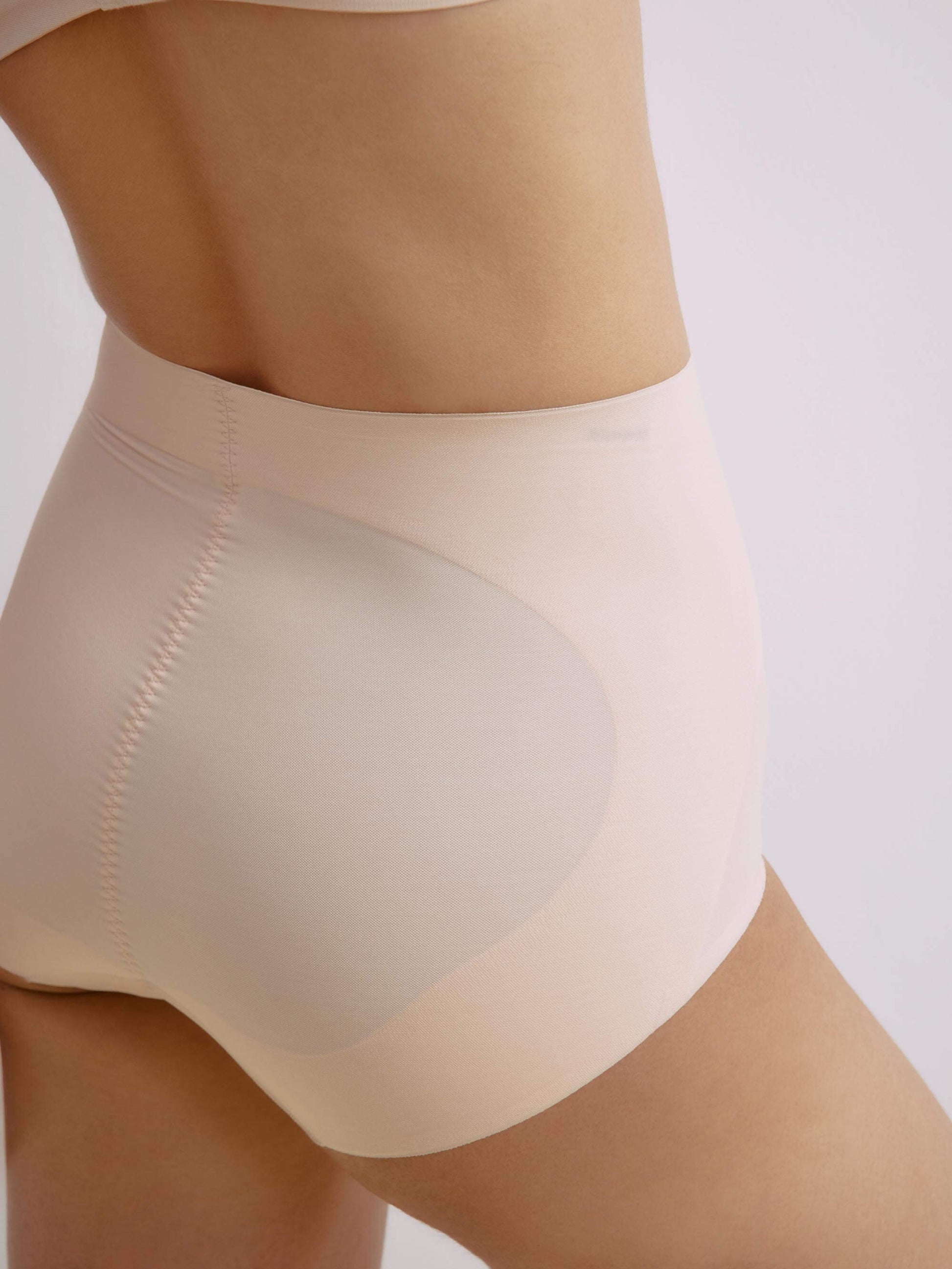 Close-up side view of a model wearing nude high-waisted seamless briefs, highlighting the smooth, sculpting fit and comfortable fabric.