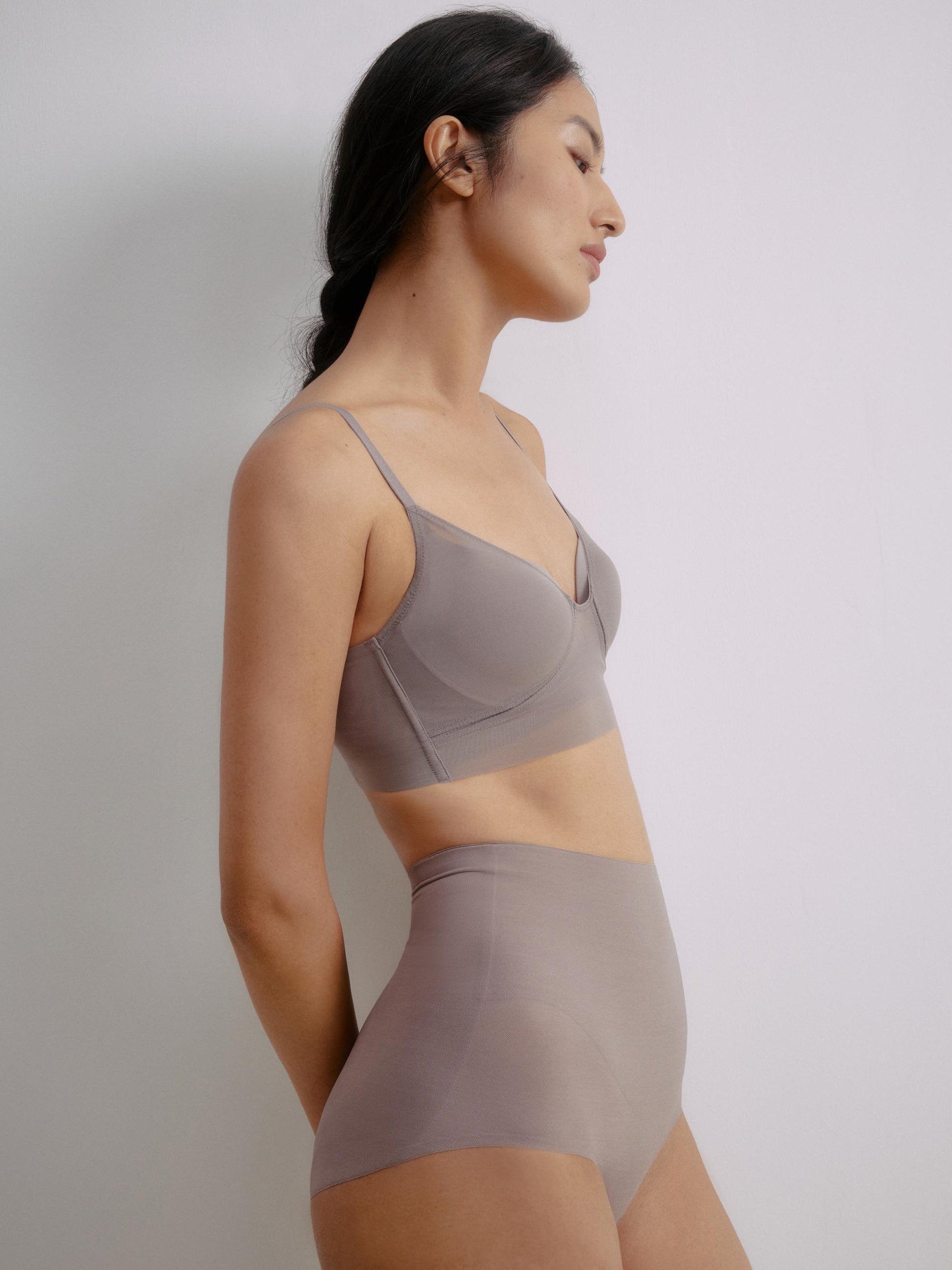 Side view of a model wearing a gray purple bra paired with high-waisted seamless briefs.