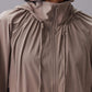 Front view of a model wearing a taupe hooded jacket with a full front zipper and drawstring details.