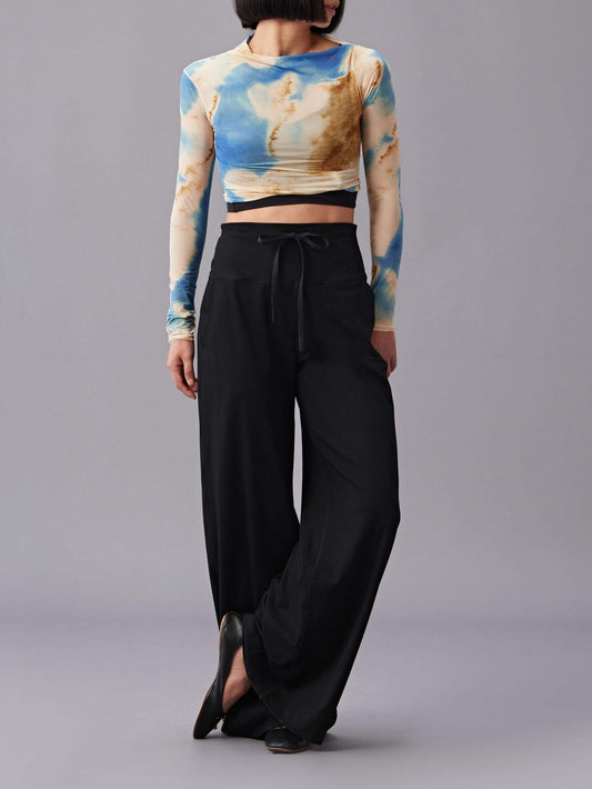 Person wearing an asymmetric long-sleeve crop top with high-waisted, wide-leg black pant.