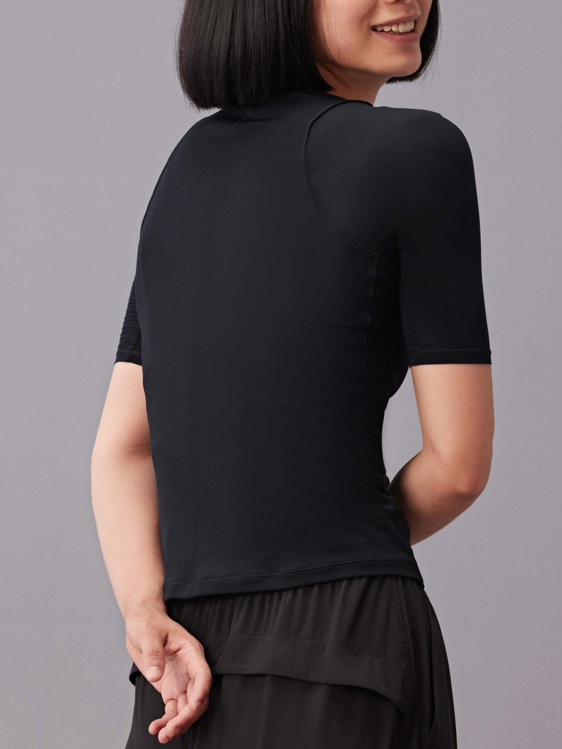 The side back of a woman wearing black round neck T-shirt.