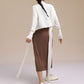 Back view of woman wearing white cardigan and brown skirt.