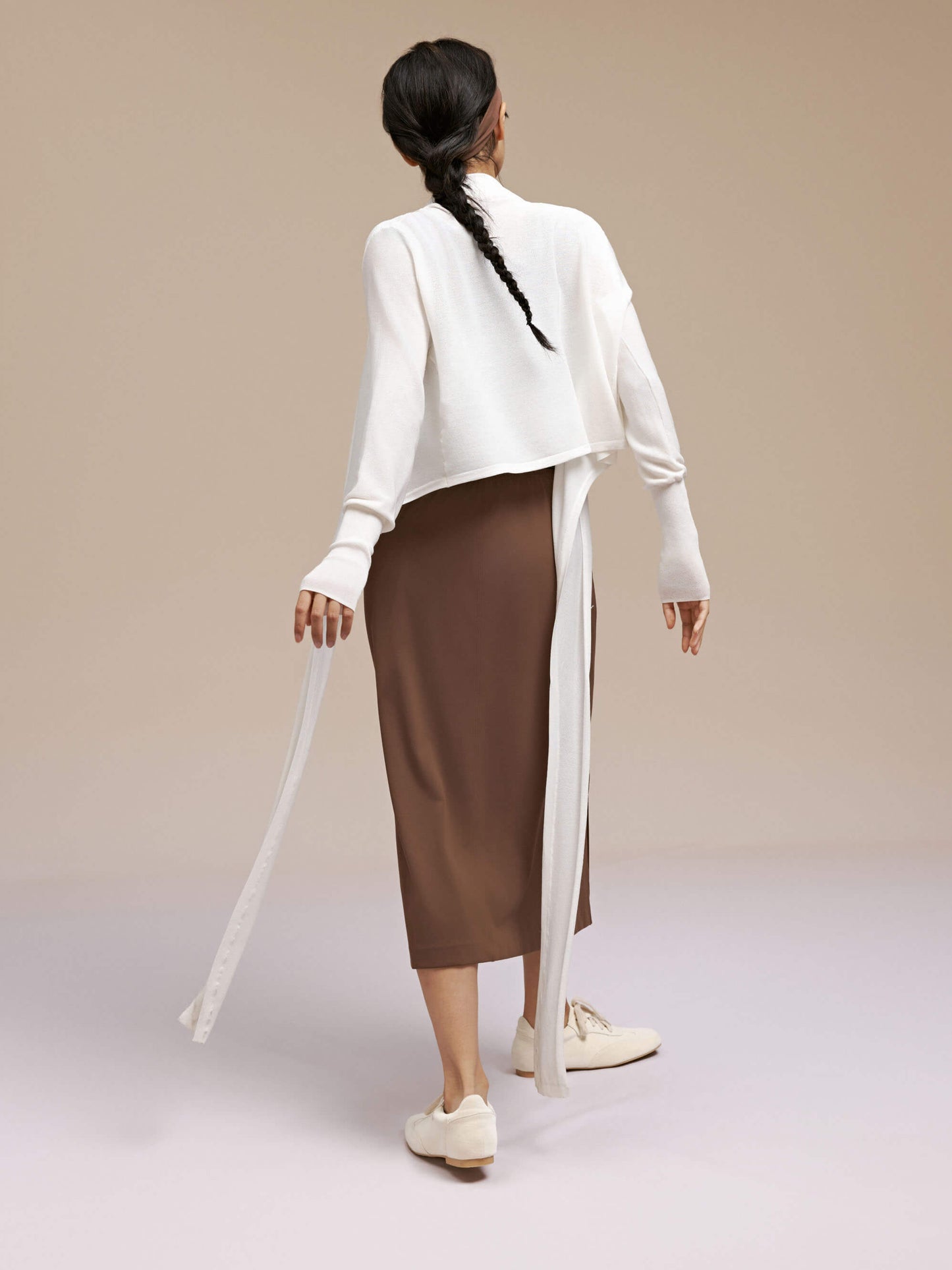 Back view of woman wearing white cardigan and brown skirt.