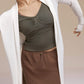 Front view of woman wearing olive green long sleeve top with white cardigan.