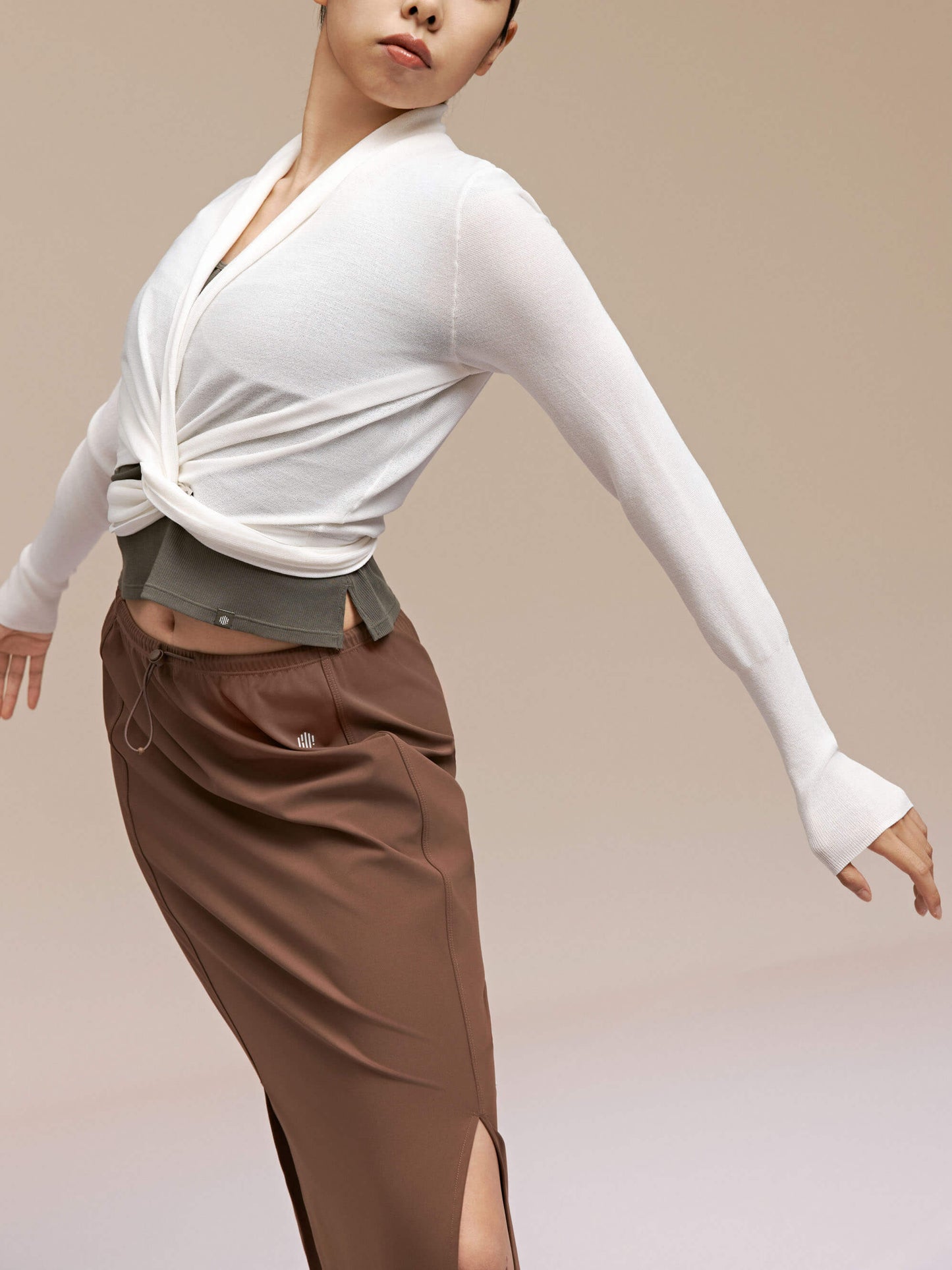 Woman wearing white cardigan with brown skirt.