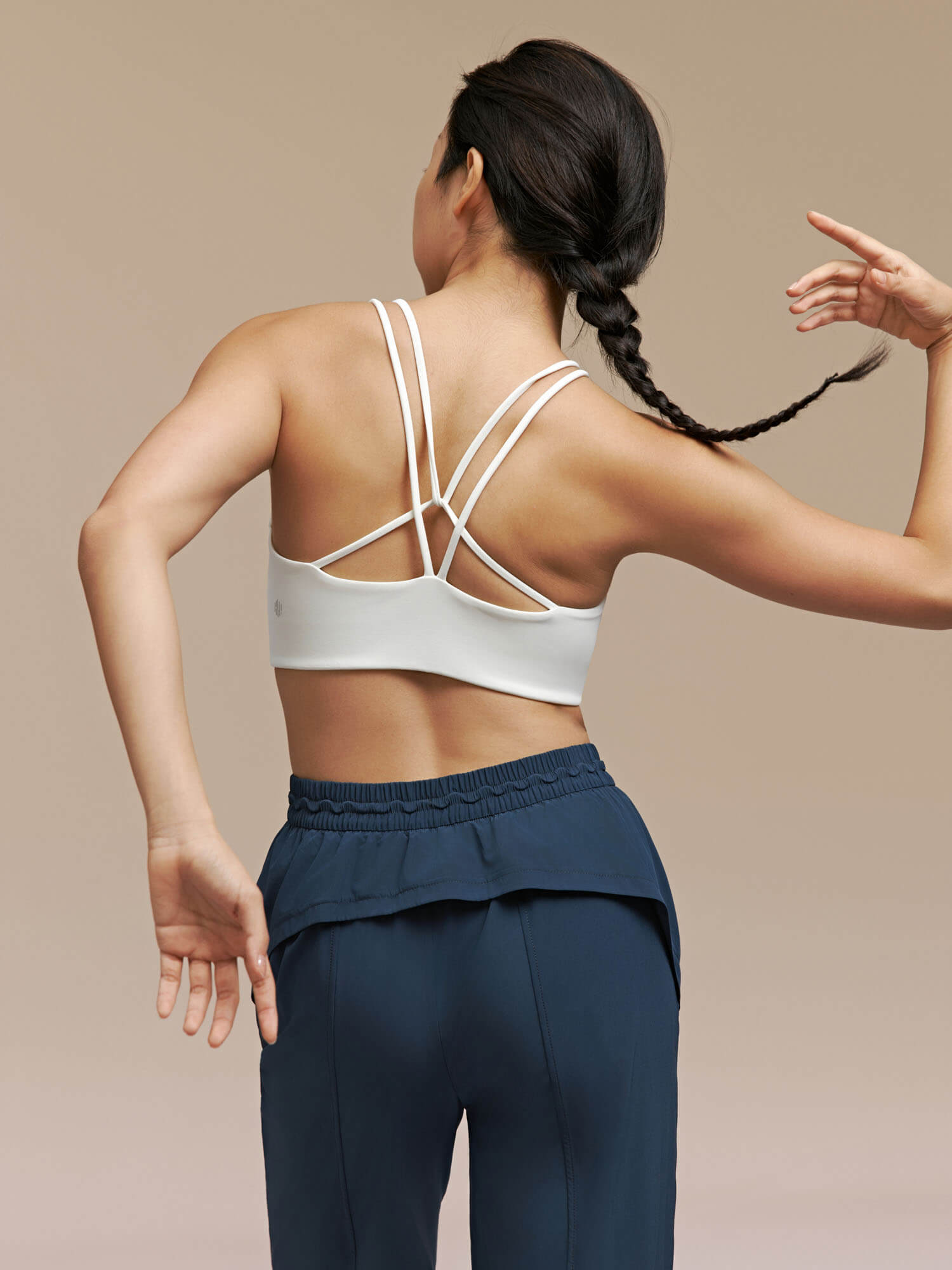 Back side of woman wearing white bra and navy blue joggers