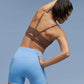 Back side of woman wearing brown sports bra and light blue biker shorts