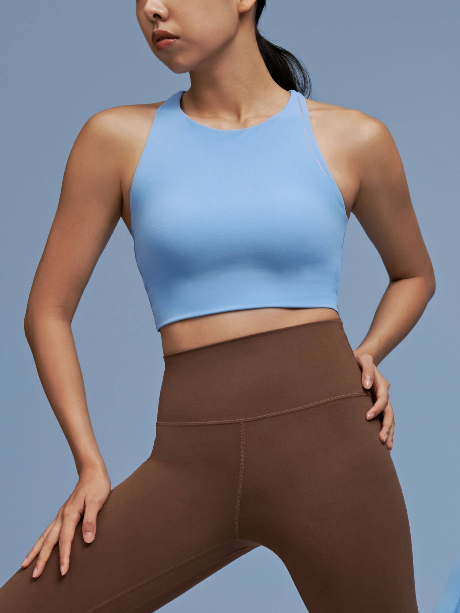 Model wearing light blue sports bra and brown leggings