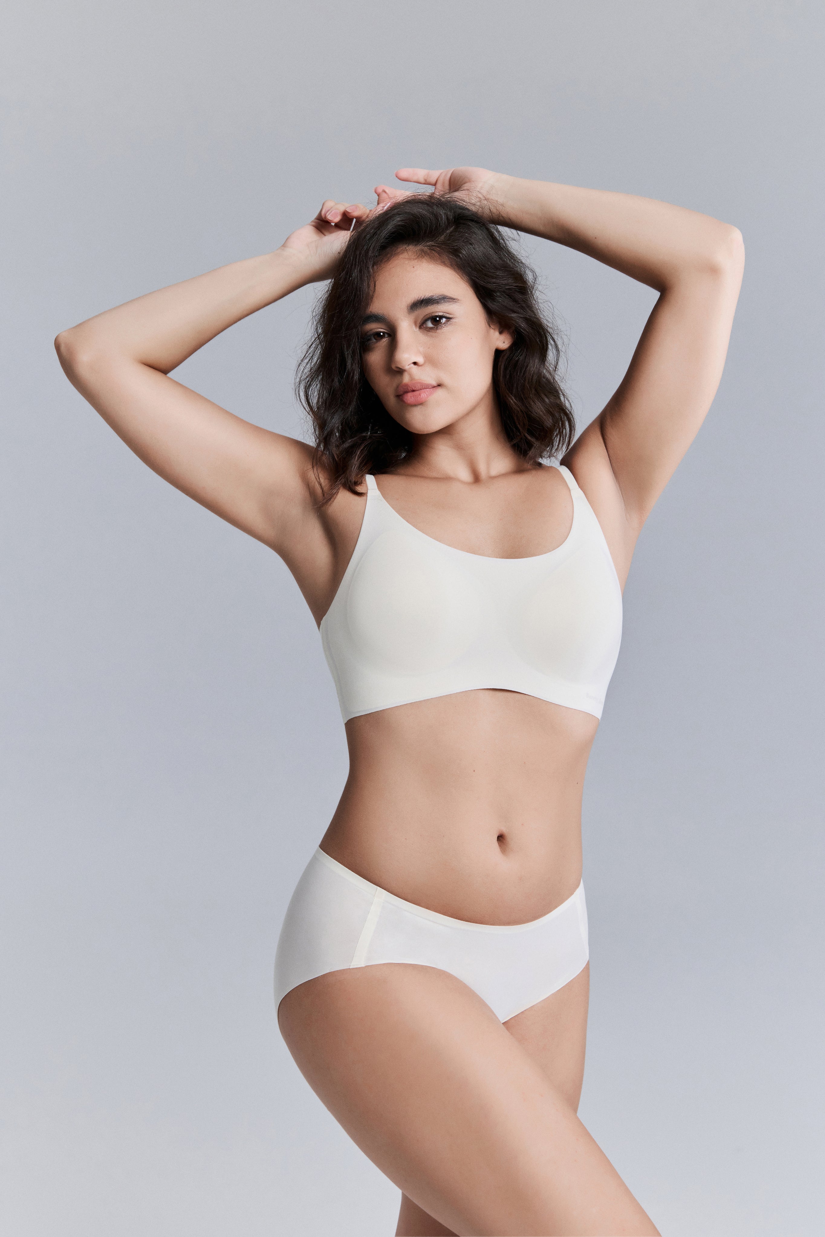 Woman wearing a white bra and panties set against a gray background
