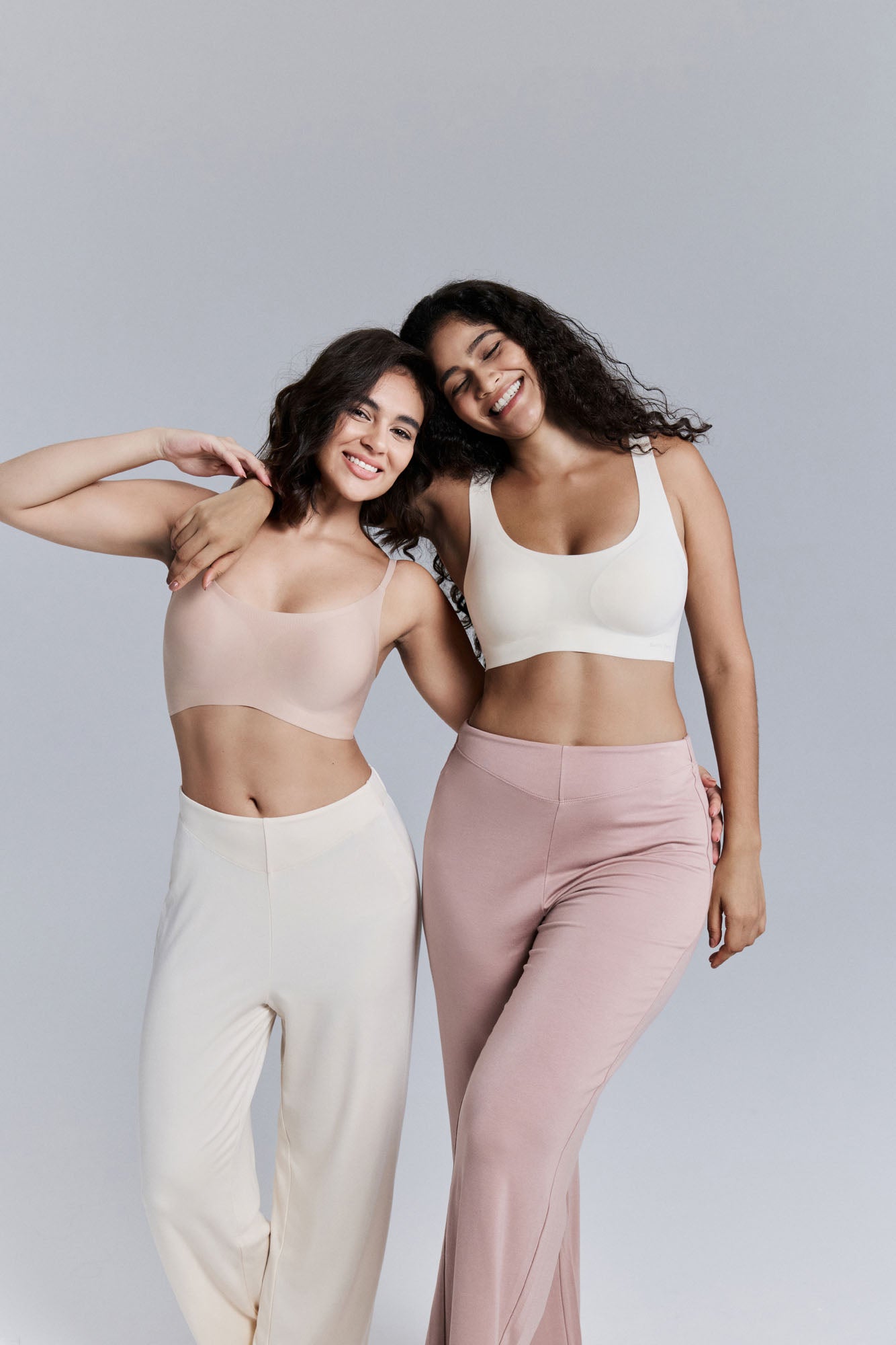 Two models posing together wearing matching athletic wear on a plain background