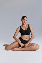Model wearing bra and brief set and sitting down.