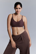 Model wearing a brown bra and pants against a gray background