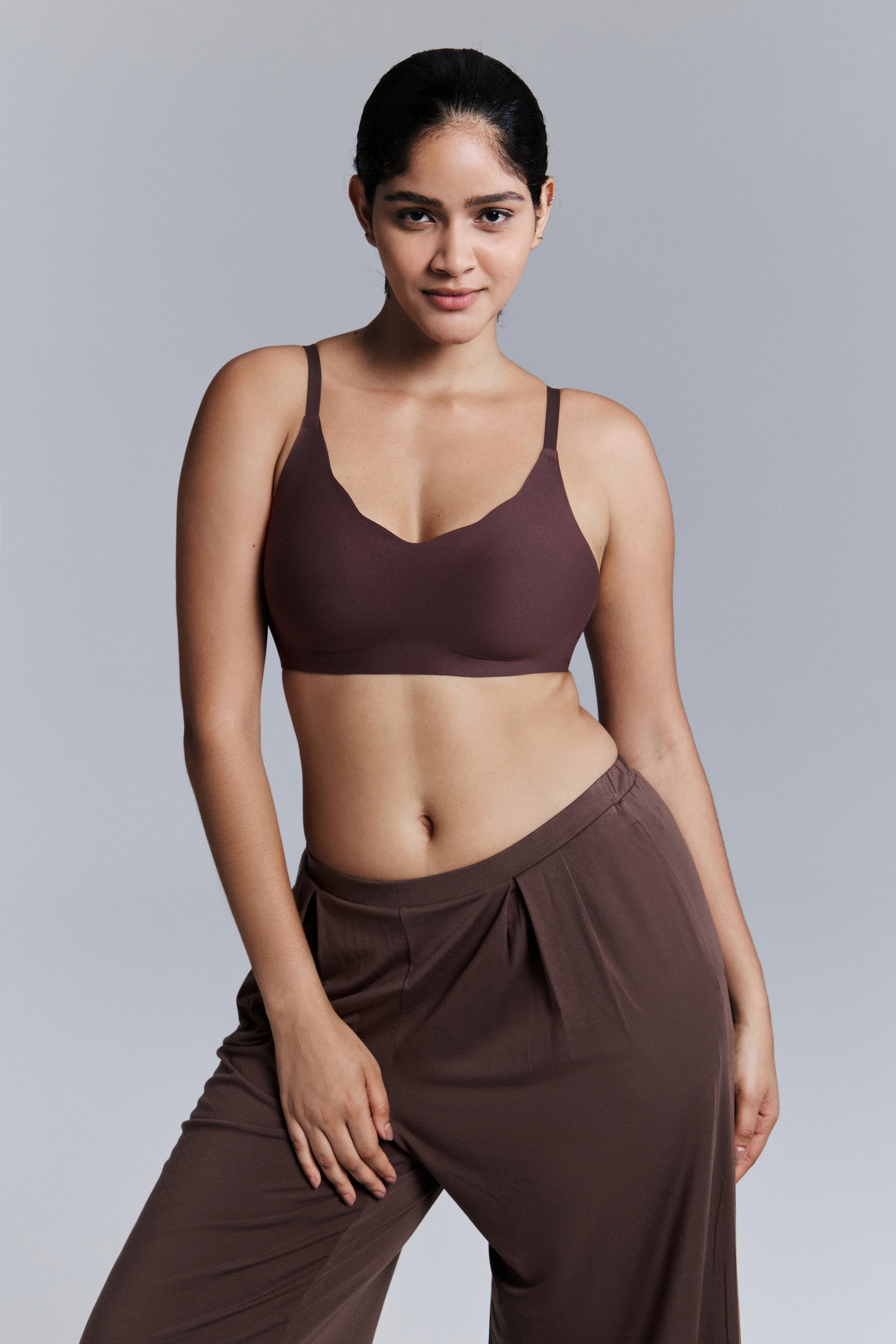 Model wearing a brown bra and pants against a gray background