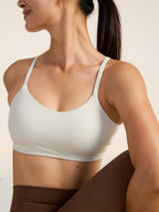Model wearing a light gray sports bra and brown leggings