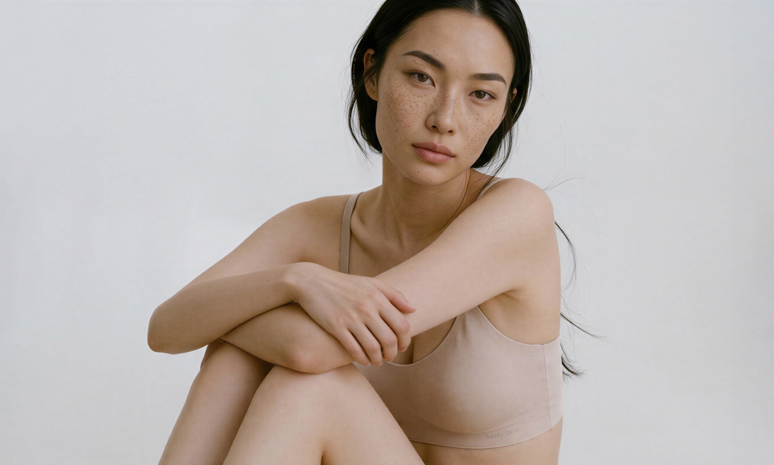 Woman wearing a beige tank top against a plain background