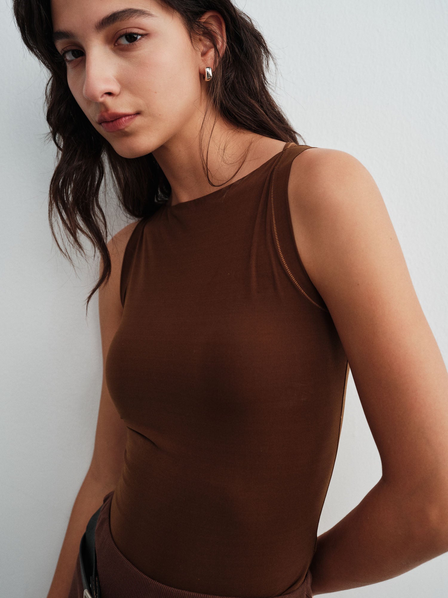 Model wearing a brown sleeveless top against a white background.