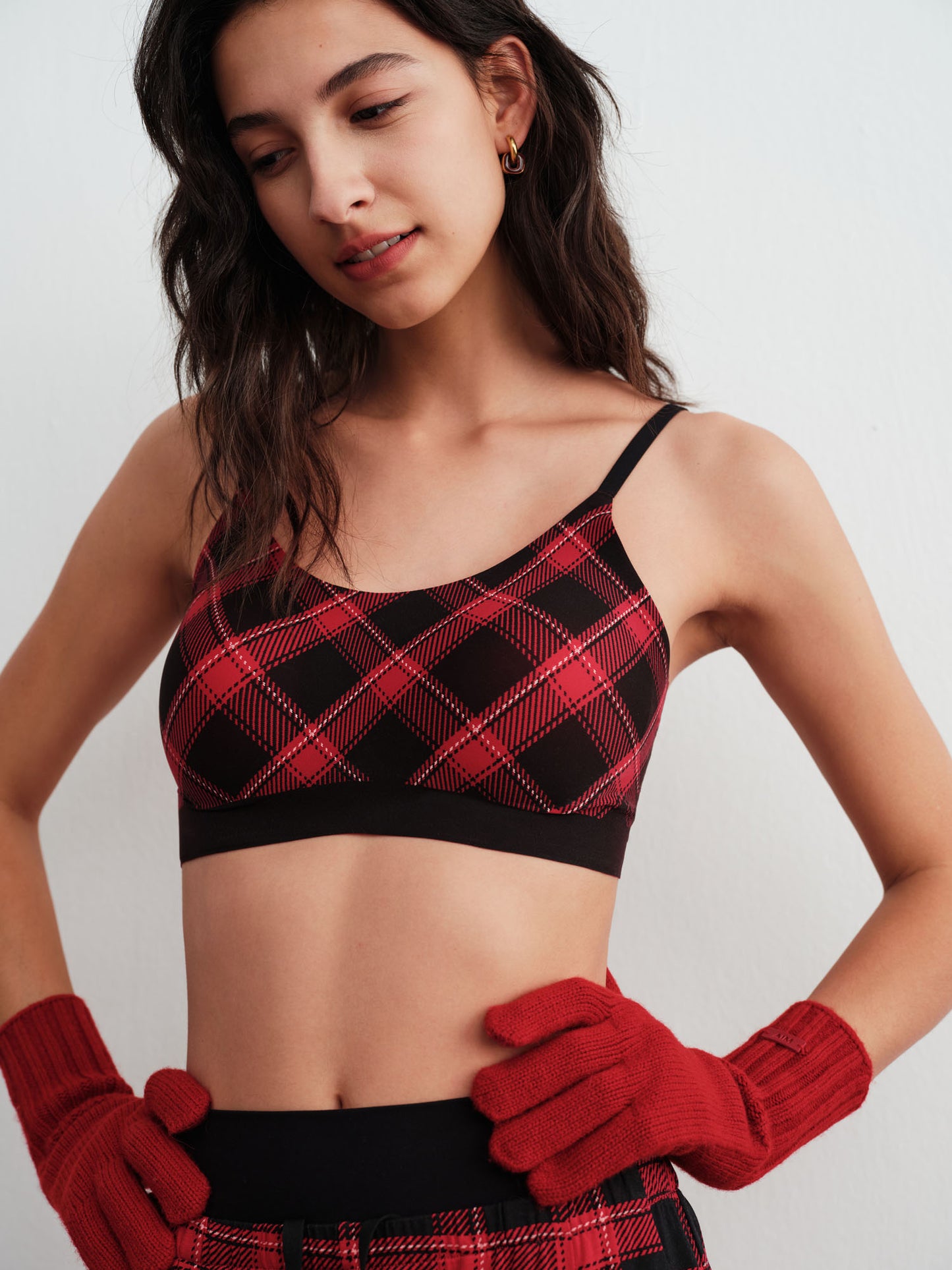 Woman wearing a red and black plaid bra and leggings with red gloves on a white background.
