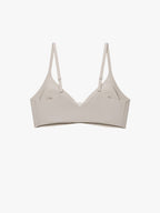 A light beige wireless bra with thin adjustable shoulder straps, displayed flat against a solid off-white background. Chateau Gray