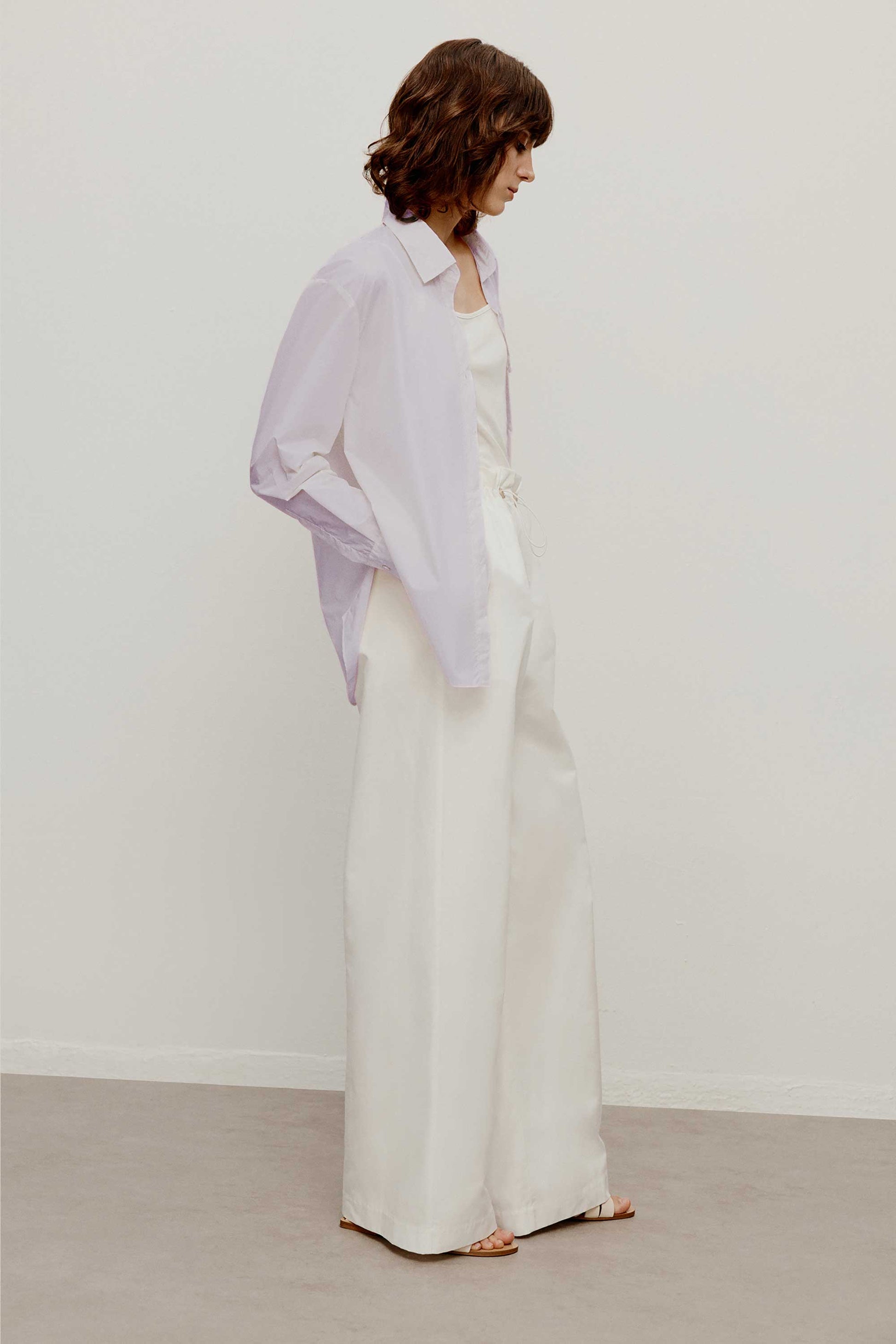 side of a woman wearing a light purple shirt.  pair with a white wide leg pants