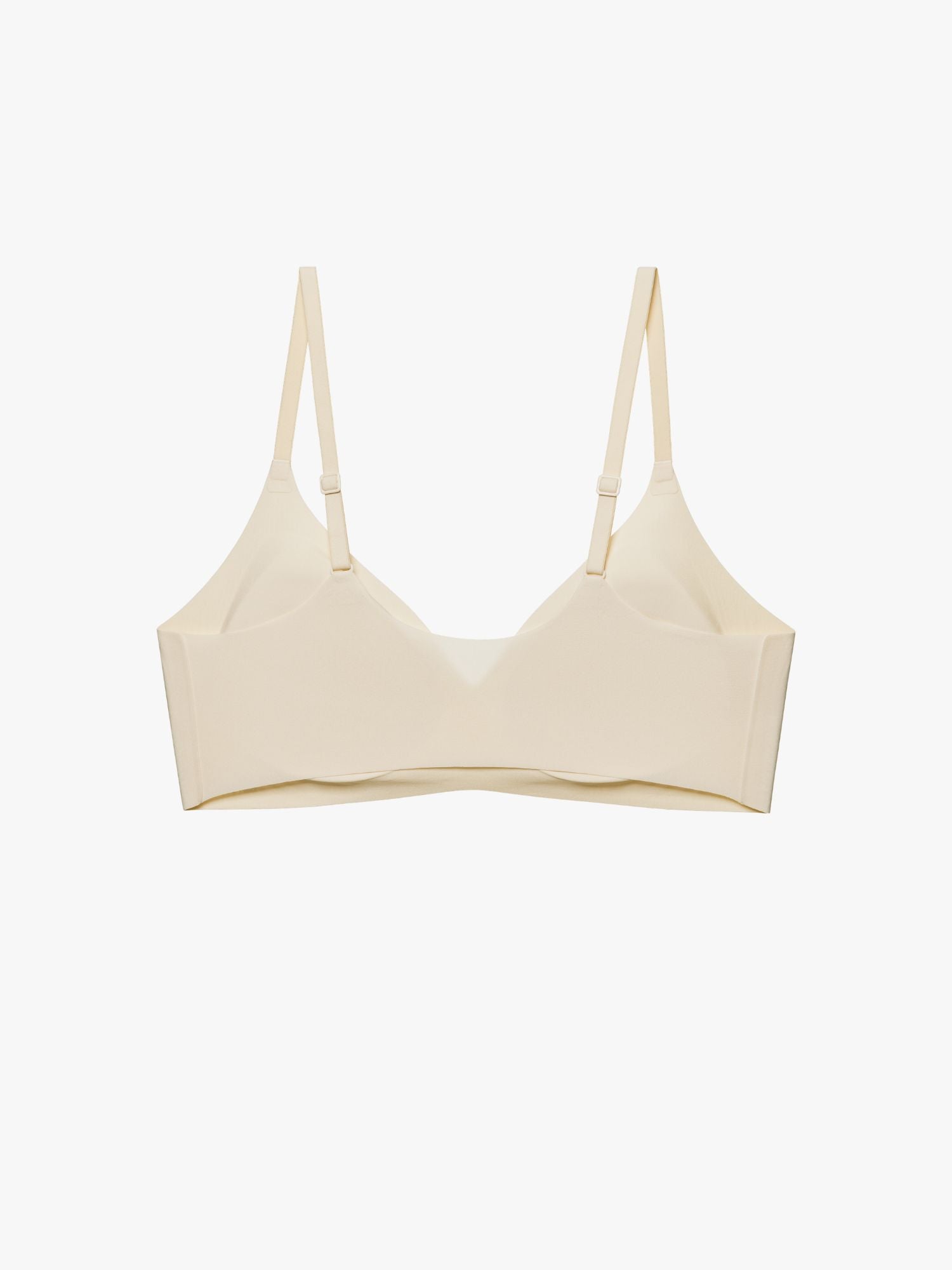 A light beige wireless bra with thin adjustable shoulder straps, displayed against a clean, solid off-white background. Eggwhite