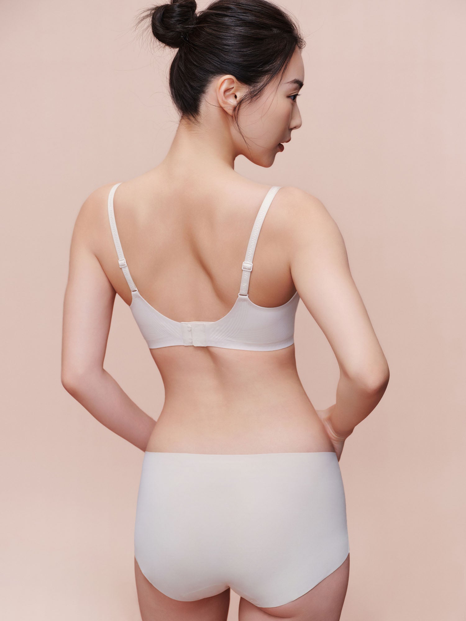 Back side of model wearing white bra and brief set.