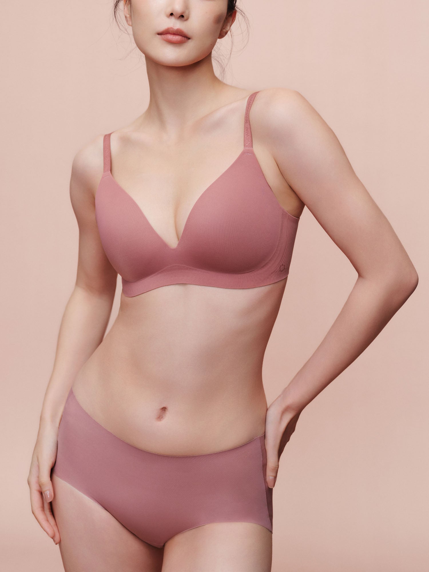 Model wearing light pink bra and brief set.