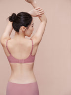 Back view of model wearing light pink bra and brief set.