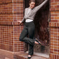 Dancer in doorway wearing gray wrap sweater, white tank top, and black legging pants