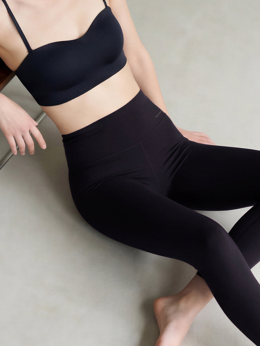 Person wearing a black sports bra and leggings on a neutral background
